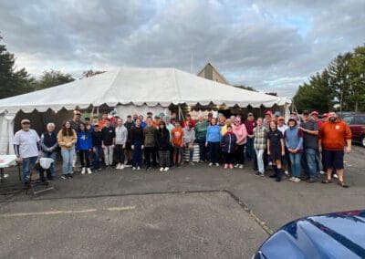 A diverse group of individuals standing in front of a tent, possibly engaged in a social gathering or outdoor event.